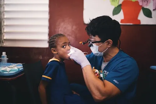 Dr. Lee wearing magnifying loupes performing a dental examination on a young child in a school setting